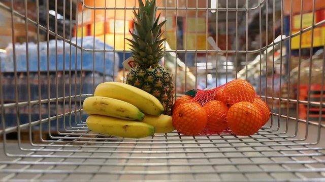 Time lapse of shopping cart with fruits moving through supermarket

