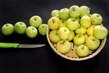 green apples in a basket on black background