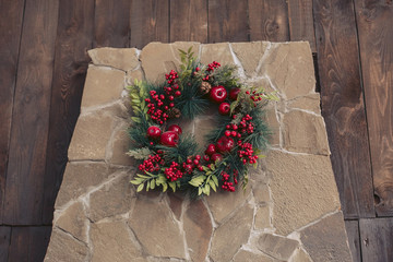 Beautiful Christmas wreath of berries and tree branches hanging on a stone wall