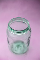 Close up of empty glass jar or storage jar or glass container isolated on pink surface.