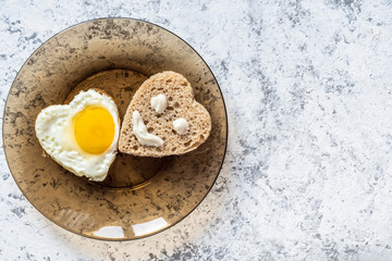 Fried egg and bread in the shape of a heart. Smiley on a piece of bread.