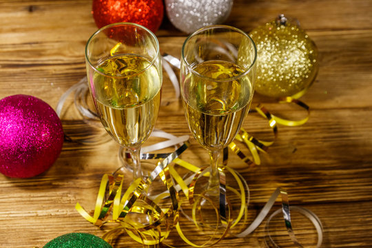 Two glasses of champagne and festive Christmas decorations on wooden table. Christmas and New Year celebration