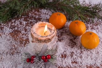 Fototapeta na wymiar Winter decoration with mandarins and burning candles and fir branches