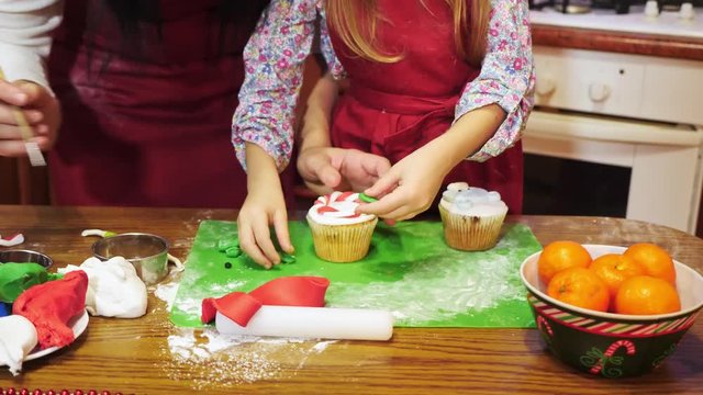 Mother and daughter are decorating with sugar mastic a Christmas cupcake