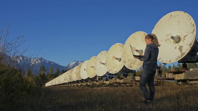 Woman student operator of institute of Solar Terrestrial Physics monitors communication equipment in notebook. Unique array solar radio telescope. Sun Solar Radio Telescope. The 'Quasar' observatory