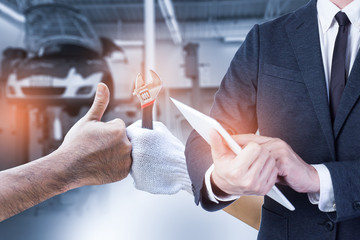 Mechanic hand checking and fixing a broken car in  garage.hand of mechanic with thumbs up and tool
