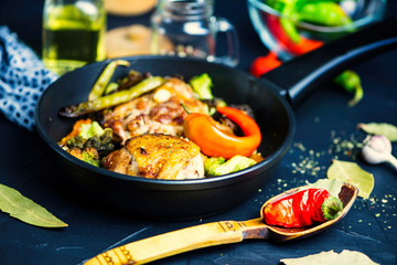 fried chicken thigh with broccoli in a spicy sauce in a pan on a black background