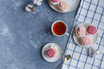 cream cakes in a plate, a cup of tea on a gray marble table. Breakfast