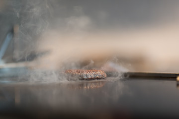 Fresh meat cutlets in a frying pan grill. A lot of steam or smoke