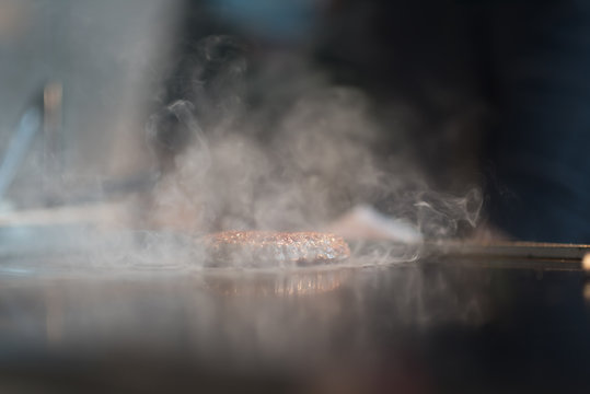 Fresh meat cutlets in a frying pan grill. A lot of steam or smoke