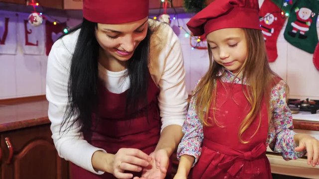 Mother kissing her daughter during they decorating cupcake