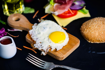 fried egg and ham with cheese, vegetables on a black background