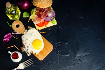 fried egg and ham with cheese, vegetables on a black background