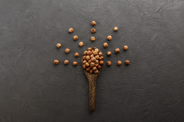 Hazelnuts in wooden spoon on dark background.