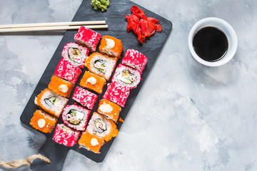 Fototapeta na wymiar Assorted sushi rolls set served on plate on concrete background