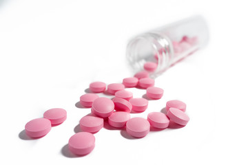 pink pills scattered on a white background.