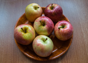 Several apples on a plate and wooden table