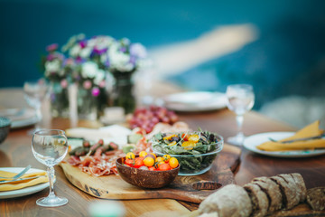 Salami and cheese platter and salad on a wooden table in the garden