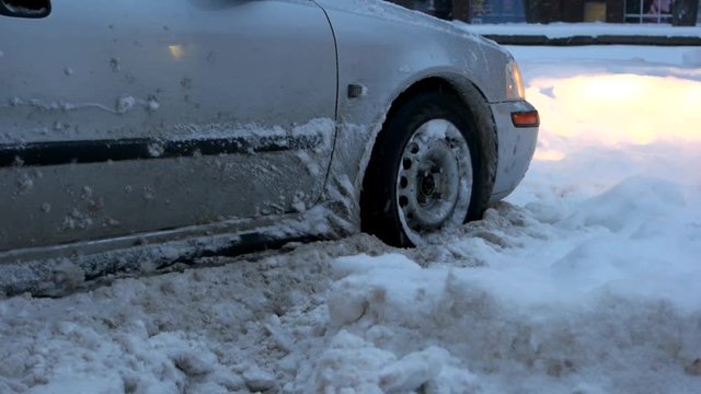 Car stalled in the snow. Close up of car wheel stuck in snow drift. Did you buy winter tires?