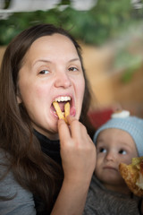 Closeup portrait. Beautiful young woman having fun eating French fries . small baby on the background