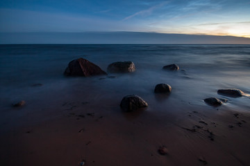 Fototapeta premium long exposure sea beach with rocks and washed out waves of water