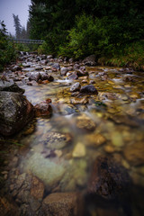 long exposure rocky mountain river in summer with high water stream level