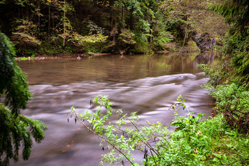 long exposure rocky mountain river in summer with high water stream level