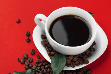 Coffee cup with coffee beans on red background.