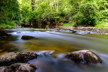 Naklejka na ściany i meble long exposure rocky mountain river in summer with high water stream level