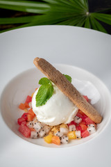 Beautiful presentation of vanilla ice cream and mixed fruit in white dish