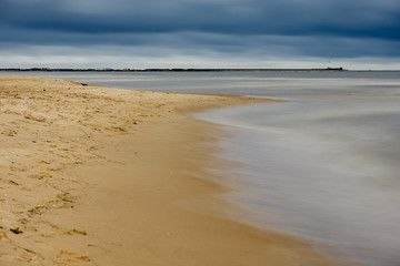 long exposure sea beach with rocks and washed out waves of water