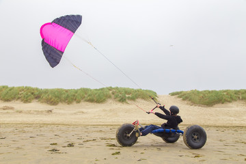 Teenage boy drives buggy with kite on beach