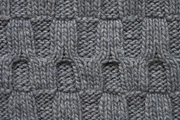 Gray knitted texture with a relief pattern. Handmade Knitwear. Background