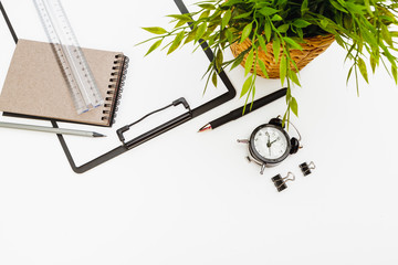 Clipboard with office supplies on white table, top view