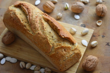 Pan de cereales sobre una tabla de madera, nueces y frutos secos