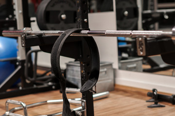 A gym with a lifting dumbbell bar and a lifting belt. sports, lifting equipment;