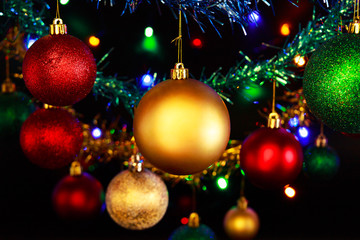 Close up of hanging Christmas decorations against a black background.