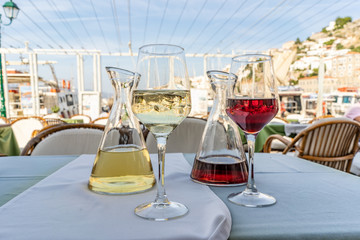A carafe of white wine with ice and a carafe of red wine, with glasses, ready to drink at an...