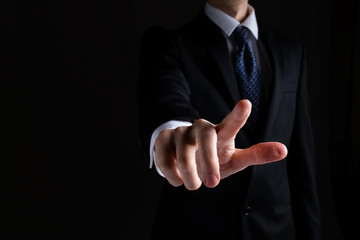 Man in a suit pointing or pressing something on black background