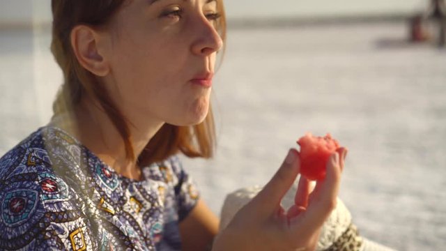 happy smiling girl enjoying the sunset, eating watermelon, sit on salt, close-up