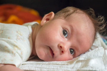 The newborn (one month old baby) lying on the bed and enjoys it