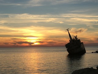 Beautiful sunset on the sea with the sunken ship shipwreck or wrecked cargo ship abandoned on sea bay
