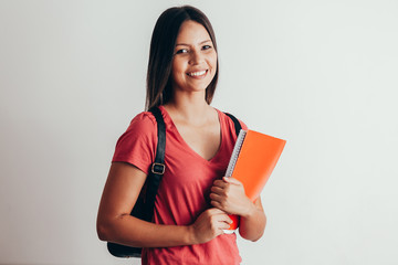 Portrait of a cheerful smiling african student girl wearing backpack and holding books isolated over white background