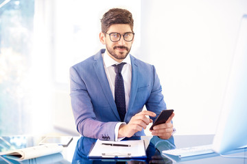 Fototapeta premium Businessman sitting in the office and text messaging