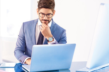 Investment advisor businessman thinking while sitting in front of notebook in the office