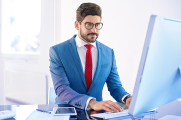 Young businessman working on his computer while sitting at office desk