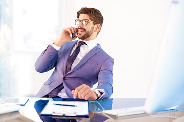Fototapeta premium Handsome young professional man making business call in the office