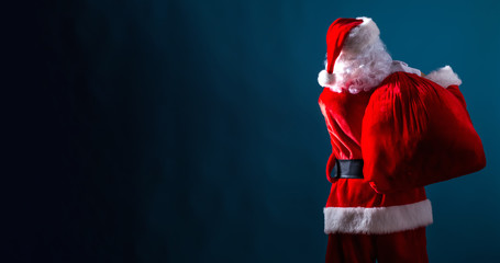 Fototapeta premium Santa holding a red sack on a dark blue background