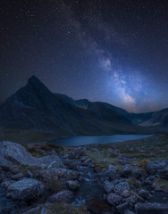 Digital composite Milky Way image of Stunning landscape image of countryside around Llyn Ogwen in Snowdonia during ear;y Autumn