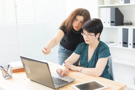 Technology, business, teaching and people concept - woman explane something at laptop another woman